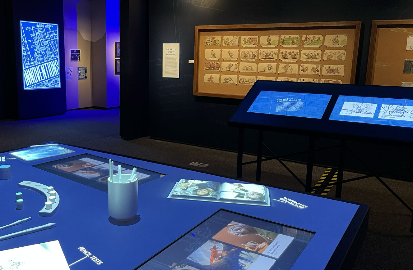 Zeichentisch mit animiertem Videomapping im Vordergrund zeigt den Entstehungsprozess von Disney-Filmen – im Raum Innoventions der Disney 100 Ausstellung, Medienkonzept und Umsetzung von cocurio