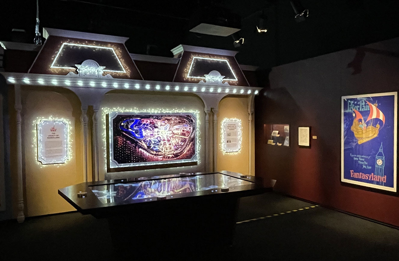 Ausstellungsbereich „Parks“ der Disney 100 Ausstellung mit großem Monitor zur Darstellung eines Disney-Parkplans und Projection Mapping mit Magic-Dust-Effekt an der Wand – Mediengestaltung und Konzept von cocurio