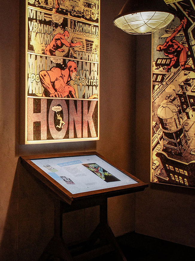 Medienstation mit beleuchteten Comicgrafiken und eingelassenem Touchscreen zur Geschichte der Marvel-Studios
