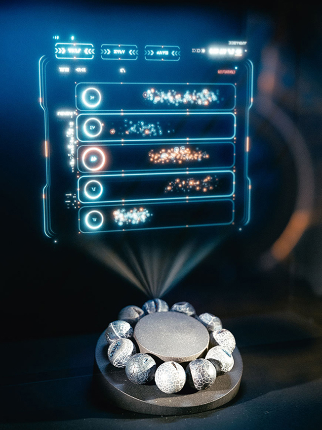Ausstellungsobjekt mit Peppers-Ghost-Projektion eines futuristischen Interfaces über einem Marvel-Armband – interaktive Medienstation gestaltet von cocurio